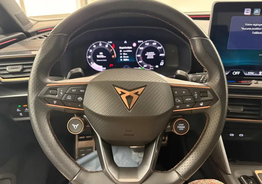 Vue rapprochée du volant noir perforé avec logo CUPRA cuivré et commandes intégrées du CUPRA Leon 2025.