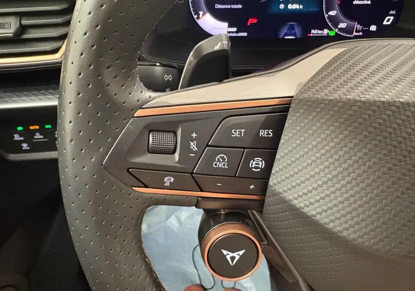 Gros plan sur le volant côté gauche du CUPRA Leon 2025 avec commandes intégrées et finition carbone.