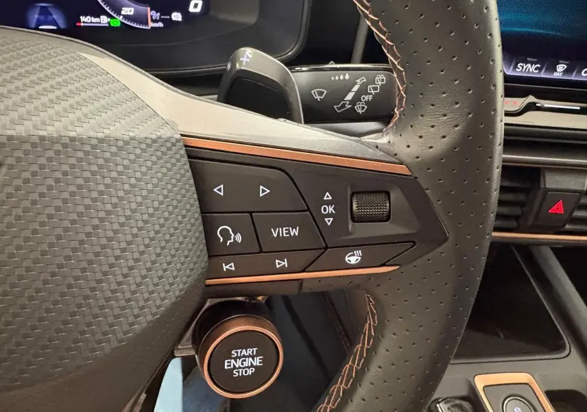 Gros plan sur le volant perforé de la CUPRA Leon blanc Nevada avec commandes multifonctions et bouton start engine stop.