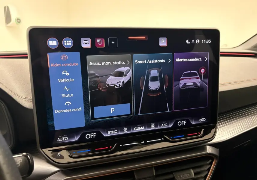 Écran tactile central du tableau de bord de la CUPRA Leon blanc Nevada, affichant les aides à la conduite et assistants intelligents.