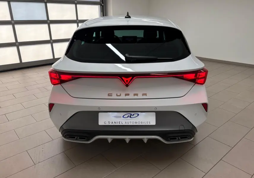 Vue arrière d'une CUPRA Leon Phase 2 blanche Nevada avec feux LED reliés et double sortie d'échappement intégrée.