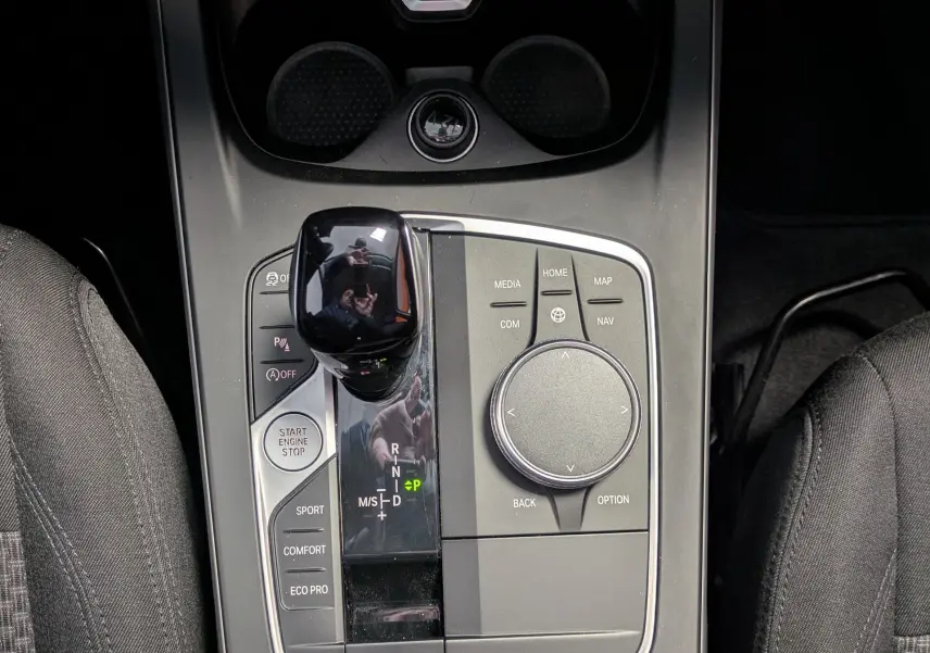 Vue plongeante sur la console centrale noire de la BMW Série 1 116d 2022 avec levier de vitesses et commandes multimédia.