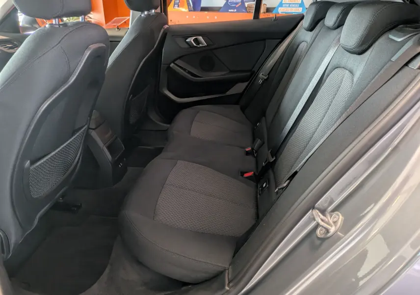 Vue côté droit de l'intérieur arrière gris d'une BMW Série 1 116d 2022, sièges tissu et ceintures visibles.