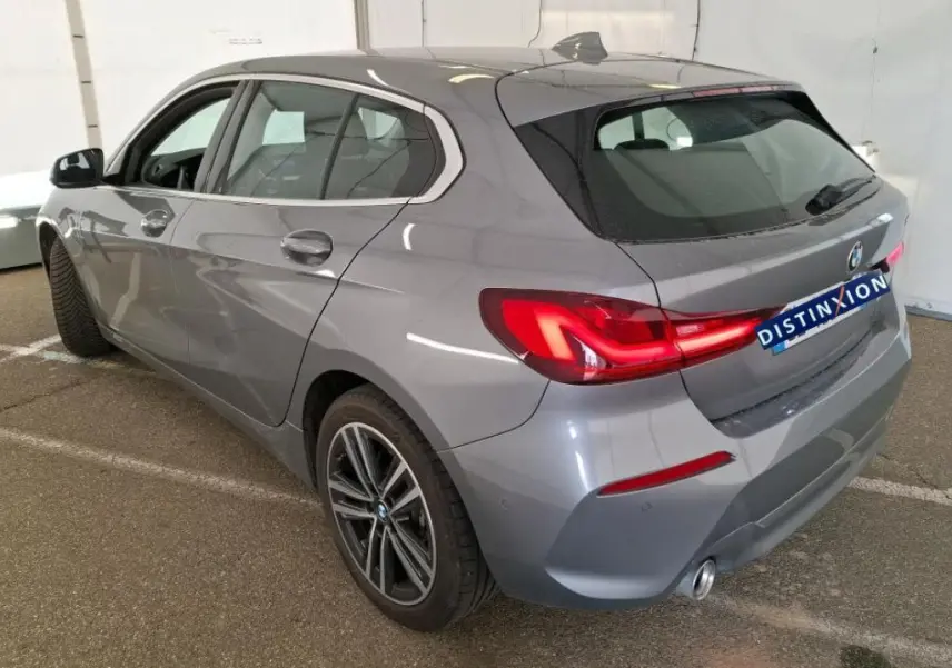 BMW Série 1 gris vue de profil côté gauche, avec jantes alliage et intérieur visible en showroom.