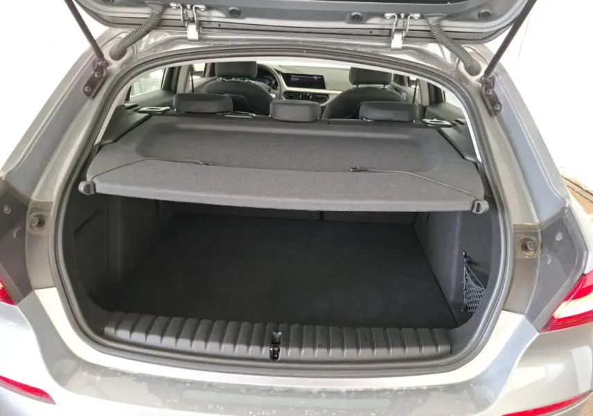 BMW Série 1 gris vue 3/4 arrière droit, jantes alliage, feux arrière LED, stationnement en intérieur showroom.