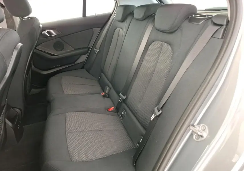 Gros plan sur les commandes de lève-vitres et réglage des rétroviseurs côté conducteur d'une BMW Série 1 gris 2022.