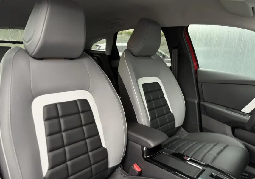 Vue intérieure des sièges avant gris clair et noir avec accoudoir central de la Citroën C4 Rouge Elixir 2025.