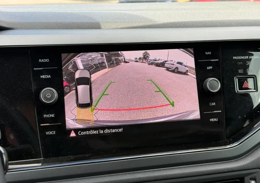 Écran tactile intérieur montrant la caméra de recul avec vue arrière et guidage vert et rouge du Volkswagen Taigo gris.