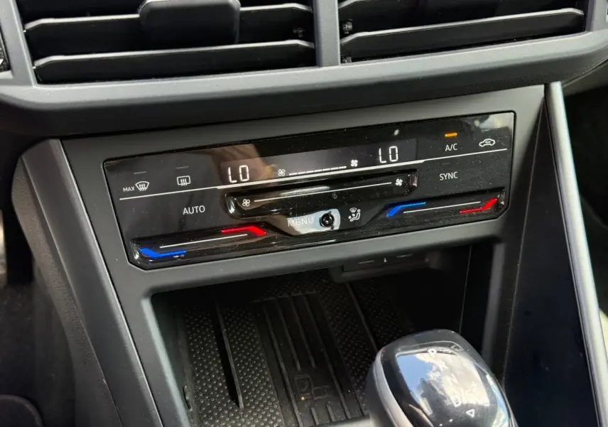 Gros plan sur la console centrale grise du Volkswagen Taigo 2025 avec commandes climatisation et levier de boîte automatique.