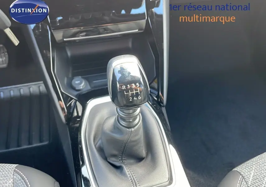 Le levier de vitesses manuel noir de la Peugeot 2008 gris Artense, vu en gros plan depuis l'habitacle.