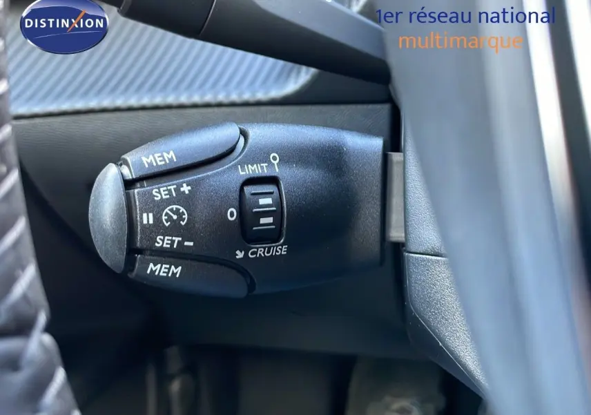 Gros plan sur la commande de régulateur de vitesse du Peugeot 2008 gris Artense, côté gauche du volant.