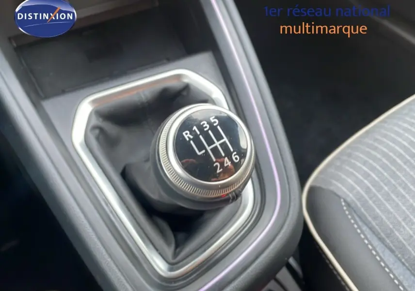 Gros plan sur le levier de vitesses manuel de la Renault Clio 2025, intérieur avec sellerie grise à surpiqûres blanches.