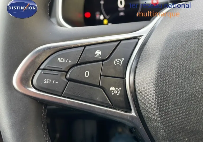 Gros plan sur les commandes au volant de la Renault Clio 2025, boutons noirs avec cadre argenté sur cuir noir.