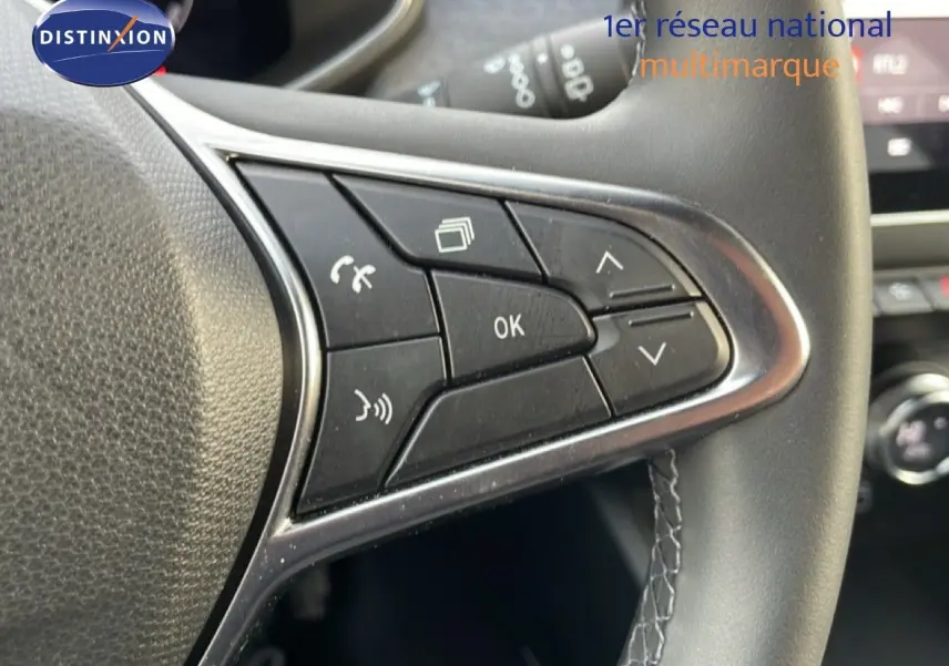 Gros plan sur les commandes au volant côté gauche de la Renault Clio rouge Désir Métal 2025, version ECO-G 100CH TECHNO.