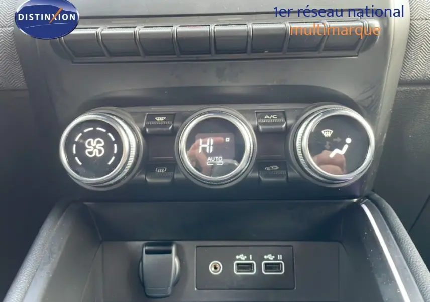 Vue rapprochée de la console centrale de la Renault Clio rouge, montrant les commandes de climatisation et ports USB.