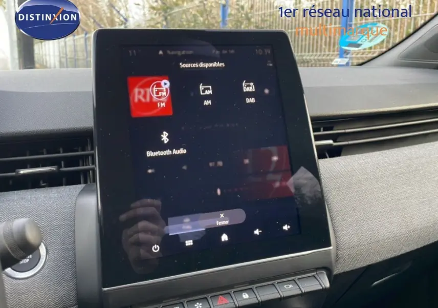 Vue intérieure centrée sur l'écran tactile du tableau de bord de la Renault Clio 2025, finition rouge désir métal.