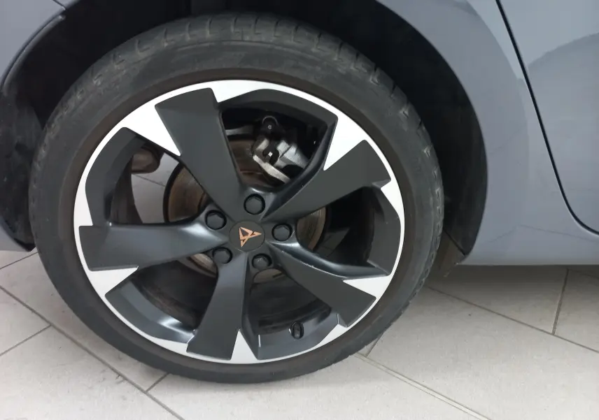 Gros plan sur la roue avant droite d'une CUPRA Leon gris Graphene avec jante noire et blanche distinctive.