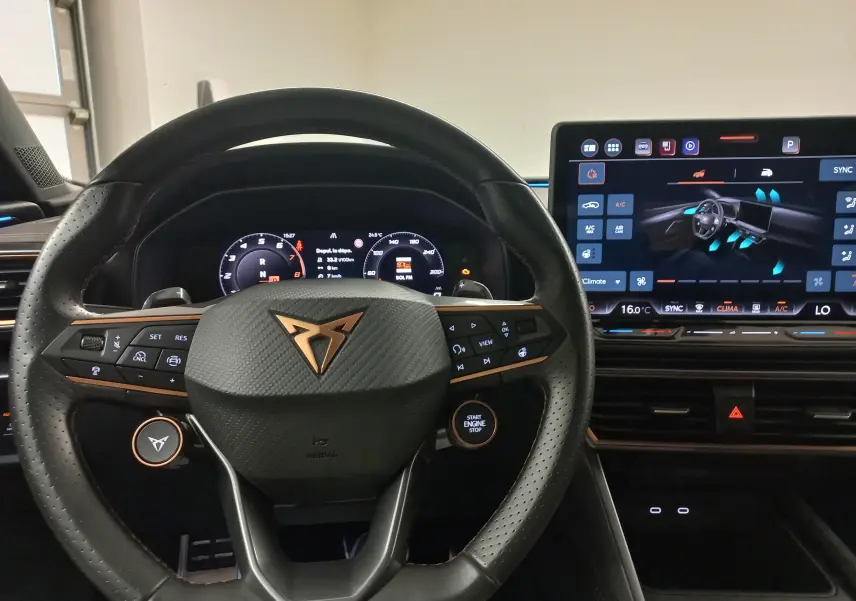 Vue intérieure centrée sur le volant noir perforé avec logo CUPRA et tableau de bord numérique lumineux.