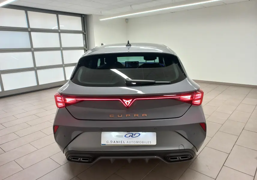 Vue arrière d'une CUPRA Leon Phase 2 gris Graphene avec feux arrière LED reliés et double sortie d'échappement intégrée.