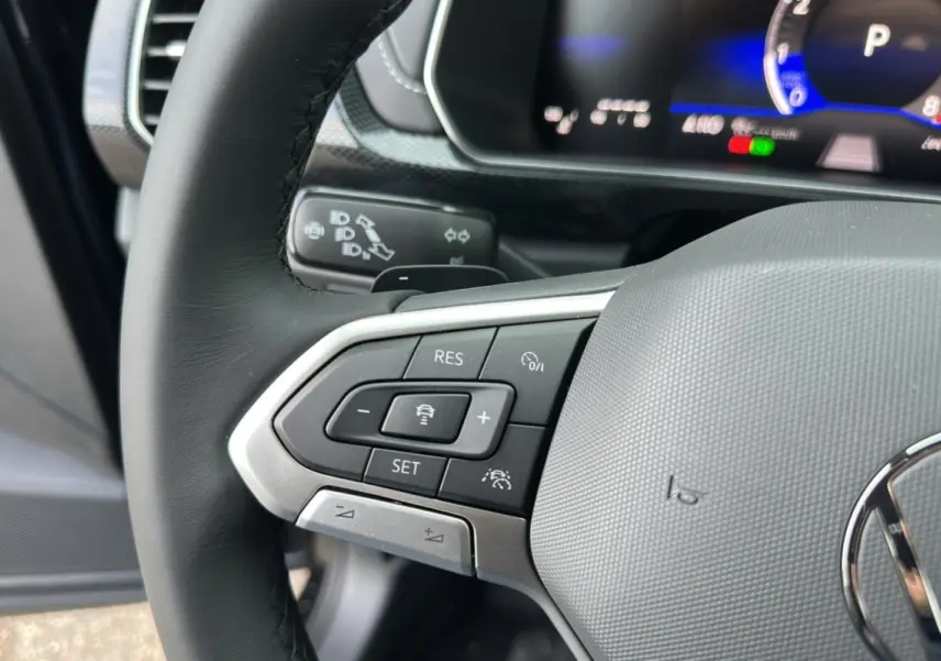 Gros plan sur le volant cuir multifonctions côté gauche du Volkswagen T-Cross noir intense avec commandes de régulateur adaptatif.