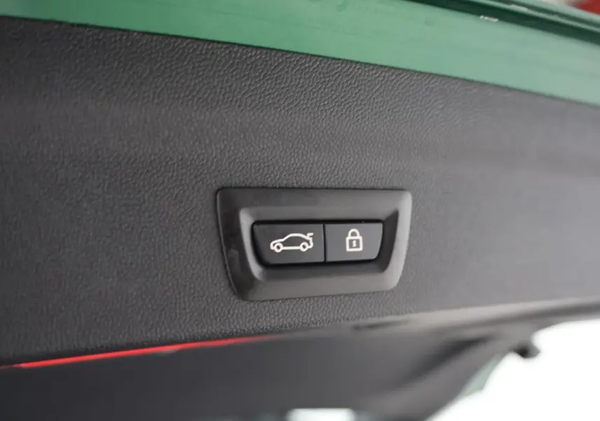 Boutons d'ouverture et de verrouillage du coffre sur la partie intérieure du hayon d'un MINI Countryman vert métallisé.