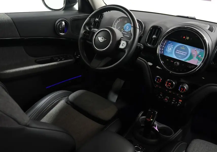 Vue intérieure côté conducteur de la MINI Countryman 136 BVA, tableau de bord avec écran tactile et éclairage d'ambiance bleu.