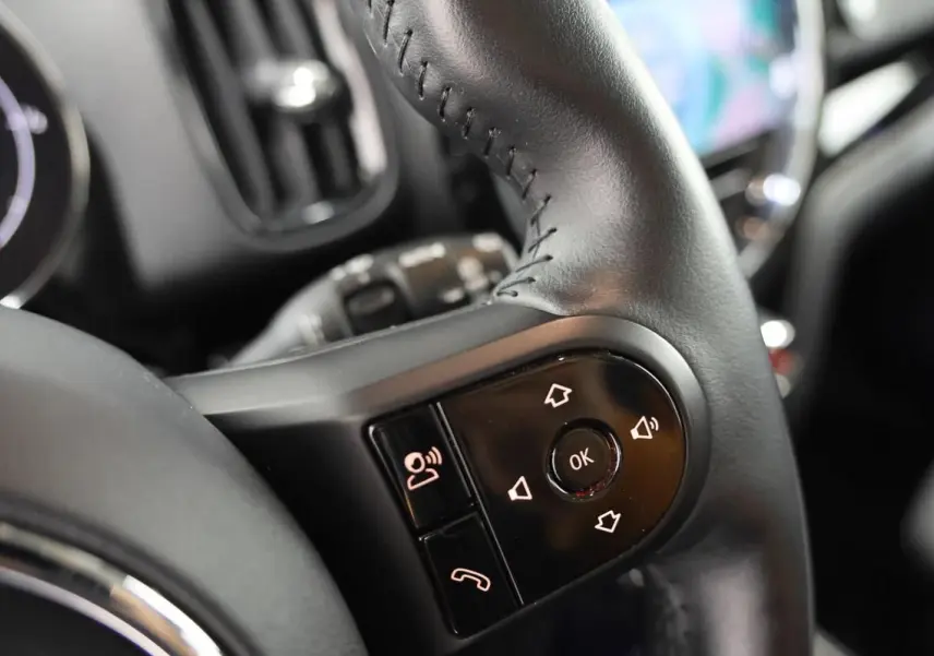 Gros plan sur les commandes du volant en cuir noir du MINI Countryman 2021, avec boutons de navigation et téléphone.