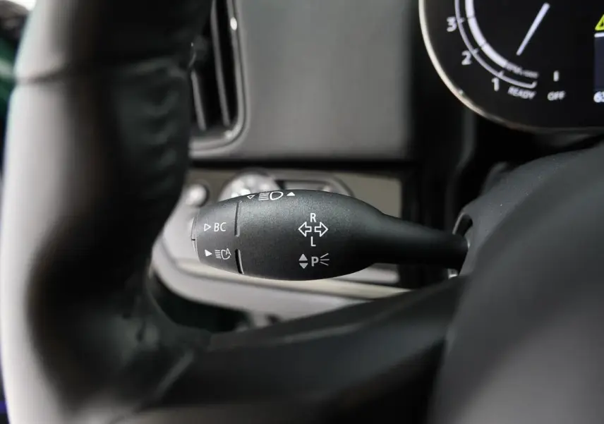 Gros plan sur la commande de clignotant à gauche du volant dans l'habitacle d'une MINI Countryman vert métallisé.