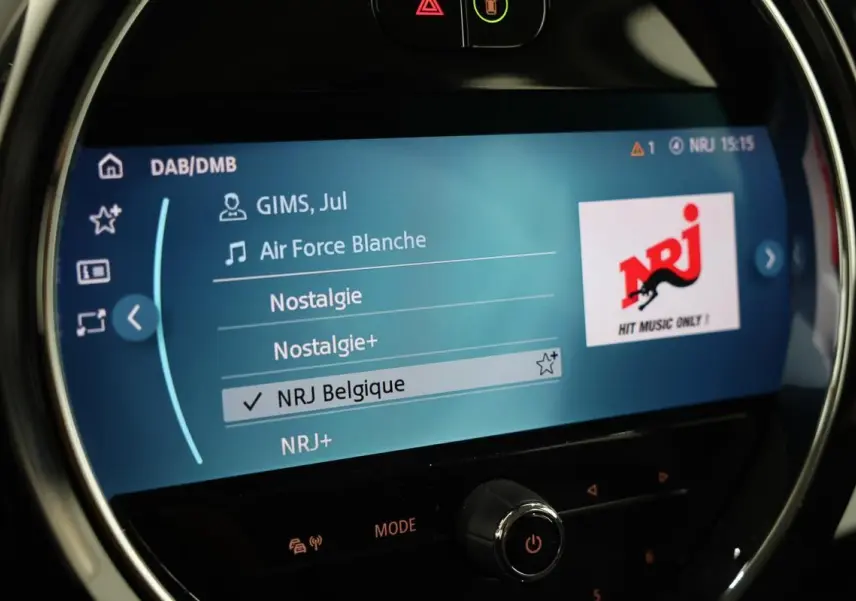 Écran central de la MINI Countryman 2021 affichant la radio NRJ Belgique avec interface moderne et cercle lumineux chromé.