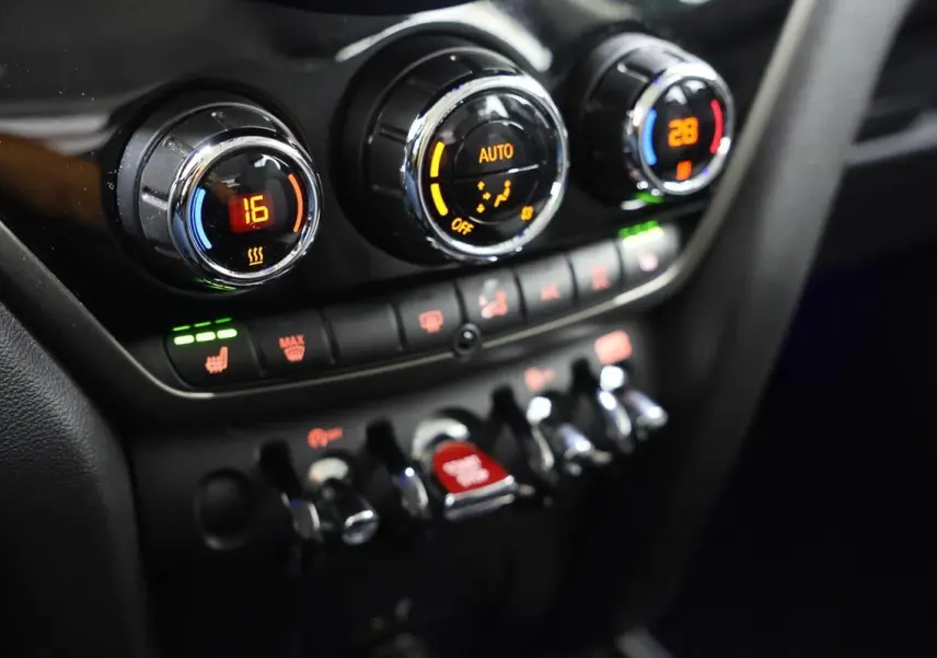 Gros plan sur la console centrale du MINI Countryman 2021, montrant les commandes de climatisation et les interrupteurs chromés.
