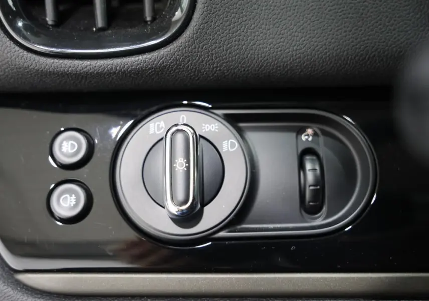 Gros plan sur la commande des phares et réglage des feux d’un MINI Countryman 2021, finition noire brillante.