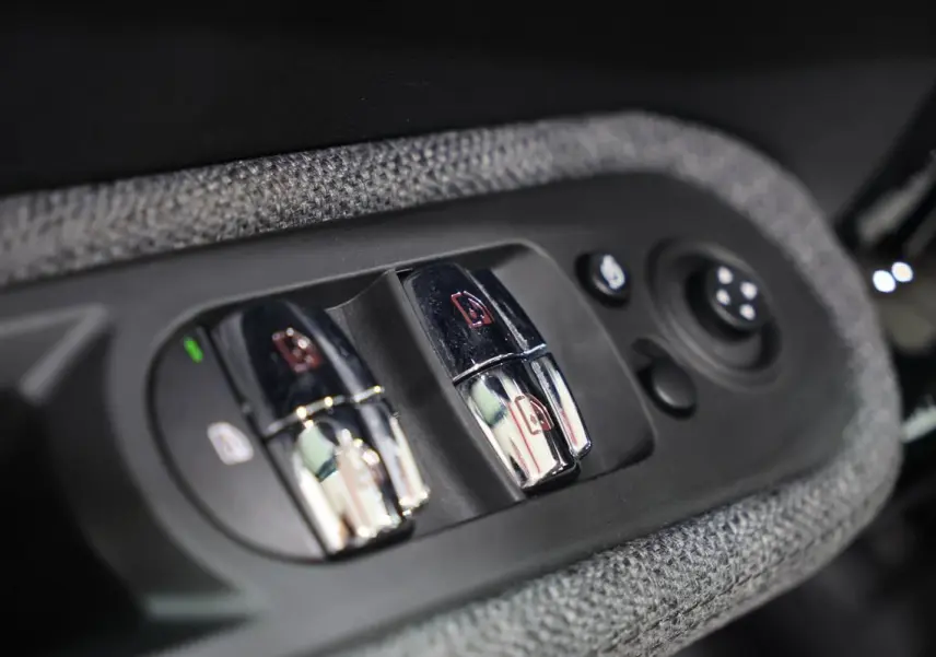Gros plan sur les commandes chromées des vitres électriques et rétroviseurs, entourées de tissu gris dans une MINI Countryman.