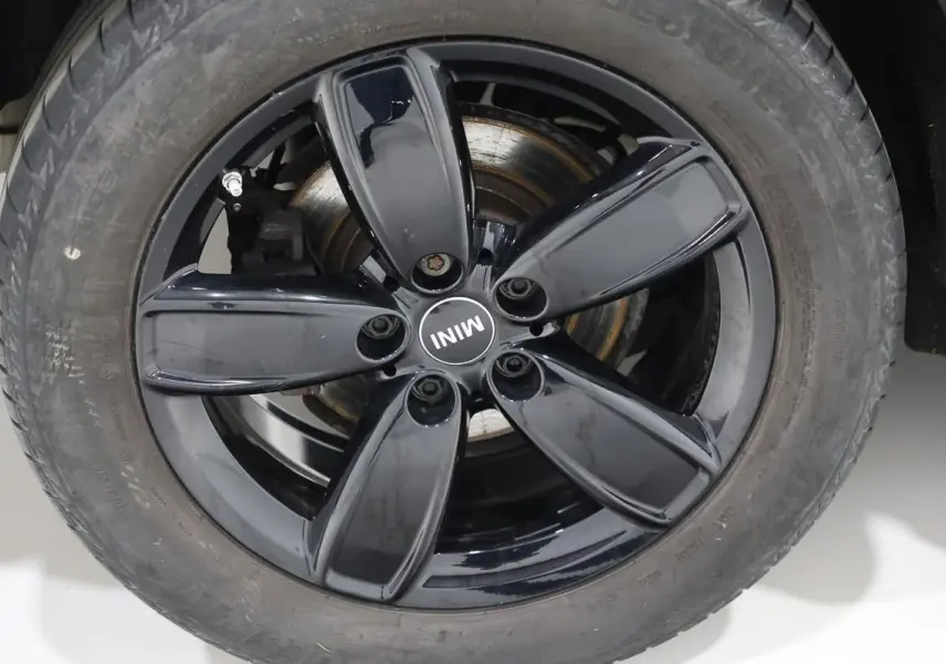 Gros plan sur la roue avant droite d'une MINI Countryman 2021, jante noire brillante avec logo MINI au centre.