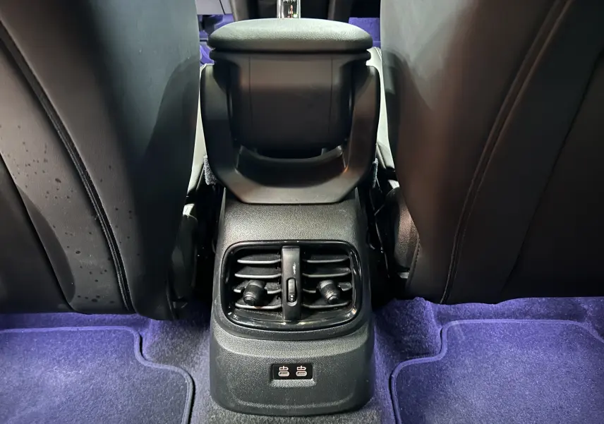 Vue rapprochée de la console arrière avec aérateurs et ports USB, sièges en cuir noir, tapis violet dans MINI Countryman 2021.