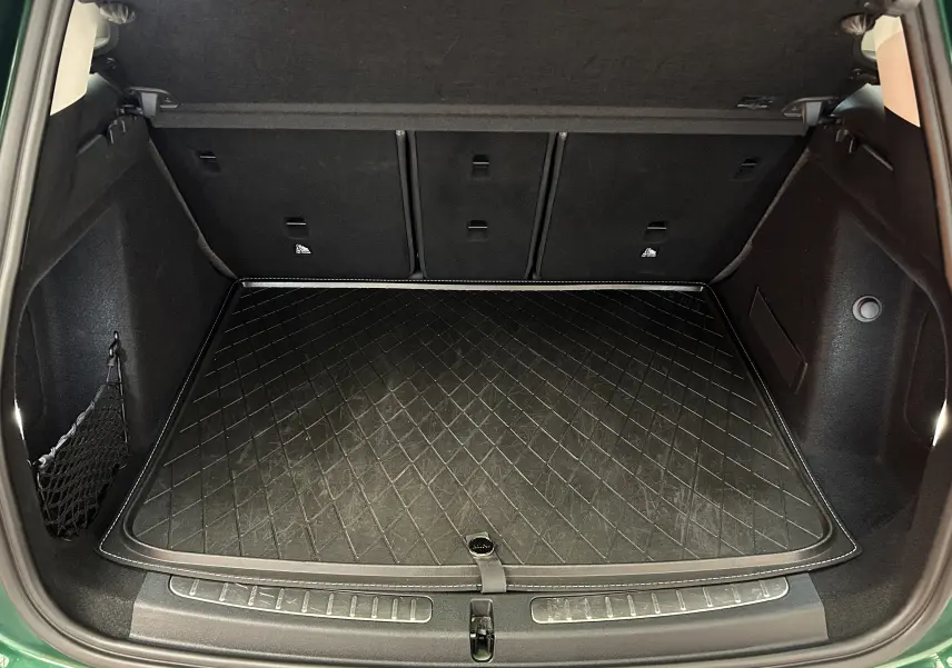 Coffre ouvert vu de l'arrière d'une MINI Countryman vert métallisé avec tapis de protection noir matelassé.