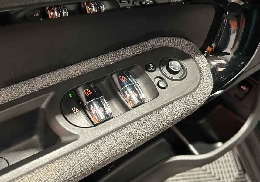 Détail des commandes de lève-vitres et réglage des rétroviseurs sur la porte côté conducteur d’un MINI Countryman 2021.