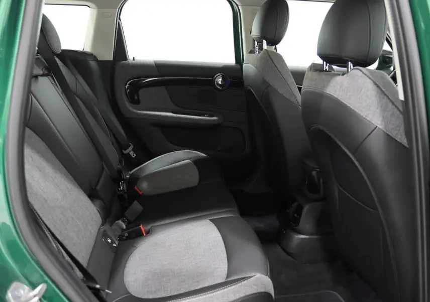 Vue intérieure arrière côté gauche d'un MINI Countryman vert métallique, sièges bicolores tissu et cuir gris et noir.