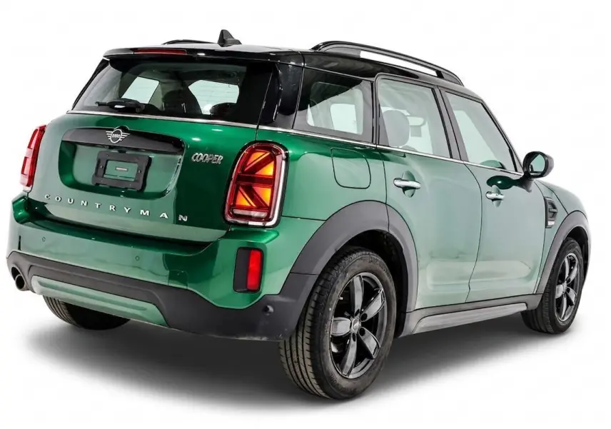 Vue 3/4 arrière droite d'un MINI Countryman vert métallisé avec toit noir et jantes noires.