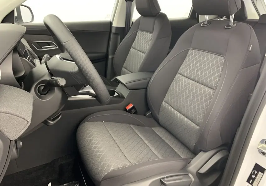Vue intérieure côté conducteur du MG ZS 2026, sièges tissu gris à motifs losanges et volant multifonction noir.