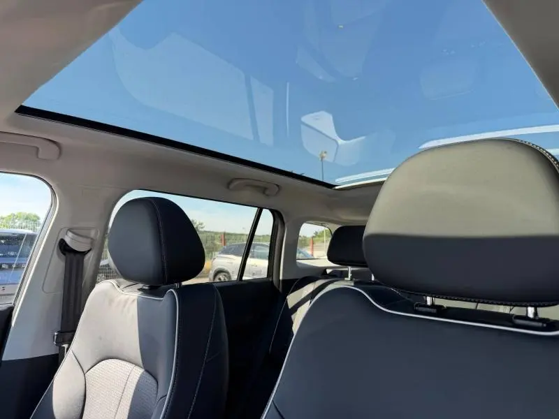 Vue intérieure avant du JAECOO J5 2026 avec toit panoramique en verre et sièges en cuir synthétique noir.