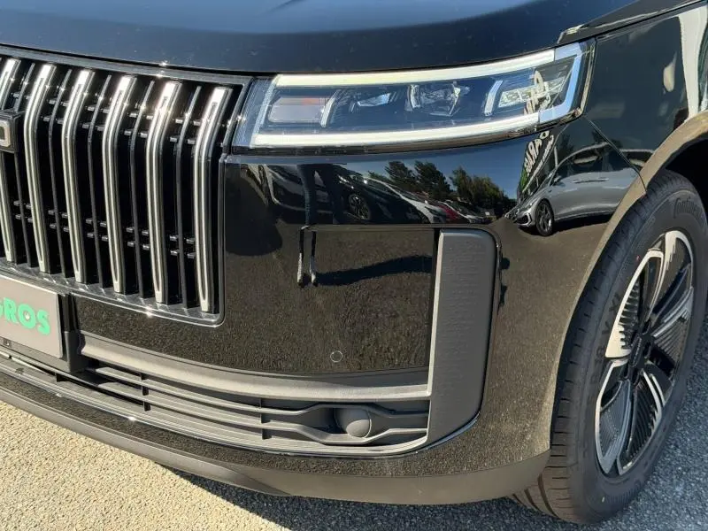 Gros plan sur l'avant droit du JAECOO J5 2026 en Carbon Crystal Black métal, mettant en valeur la calandre verticale et les phares LED.
