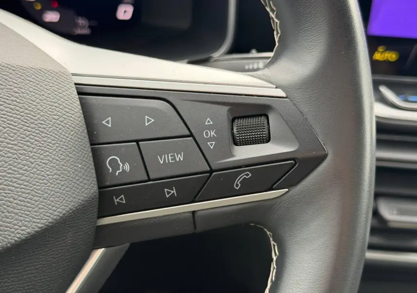 Gros plan sur les commandes multifonctions en cuir noir du volant de la SEAT LEON 2.0 TDI 2025.