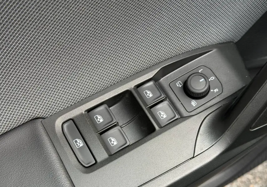 Détail des commandes de lève-vitres et réglage des rétroviseurs sur la portière côté conducteur d'une SEAT Leon gris métallisé.