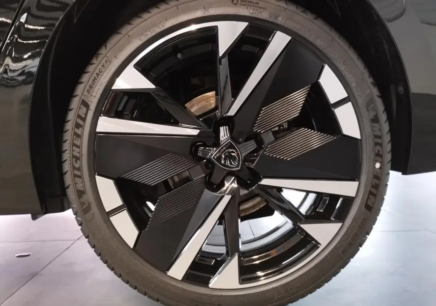 Gros plan sur la jante alliage bi-ton noir et argent de la Peugeot 308 1.2i Hybrid 2026 noir métallisé.