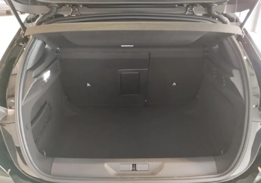 Coffre ouvert vu de l'arrière d'une Peugeot 308 noire métallisée, montrant un espace de rangement vide et propre.