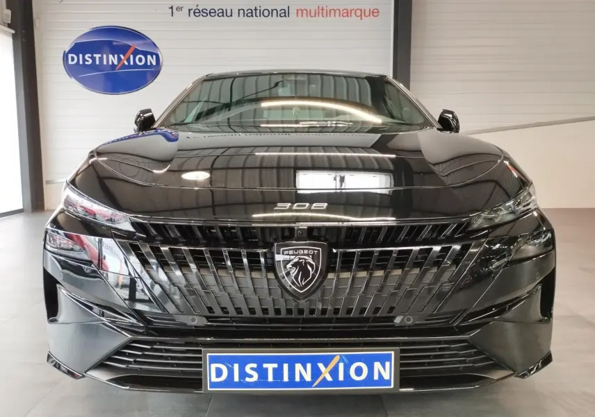 Vue frontale d'une Peugeot 308 noire métallisée avec calandre noire et logo lion central lumineux.