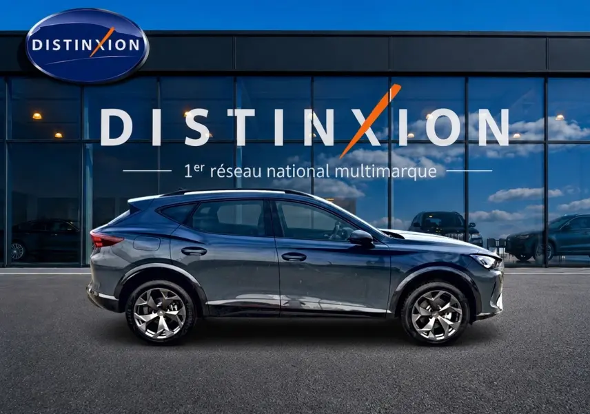 Vue latérale droite d'une CUPRA Formentor 1.5 etsi hybrid bleu fjord avec jantes 18 pouces devant une vitrine Distinxion.