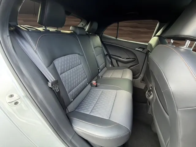 Vue intérieure des sièges arrière en cuir noir et tissu gris du MG3 1.5L Hybrid+ Luxury, avec ceinture de sécurité et porte arrière gris clair.