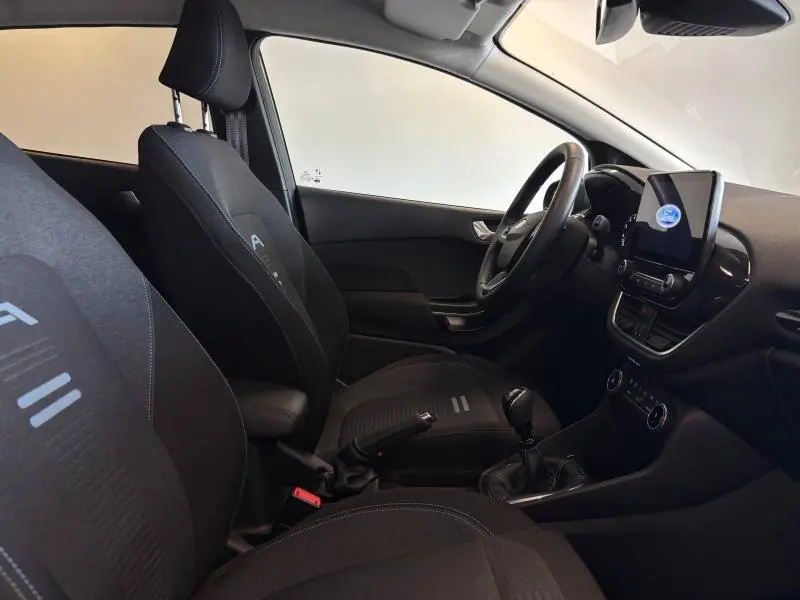 Intérieur avant de la Ford Fiesta 2022, vue côté conducteur, sièges noirs et écran tactile central visible.