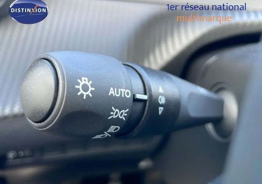 Gros plan sur la commande des phares du Peugeot 2008 blanc Okenite Metal, intérieur avec tableau de bord texturé.